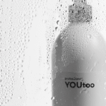 Флакон шампуня YOUtoo Hydrating Shampoo с каплями воды на стеклянном фоне — YOUtoo