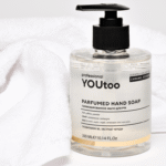 Флакон парфюмированного мыла YOUtoo Caramel Ecstasy рядом с белым полотенцем — YOUtoo