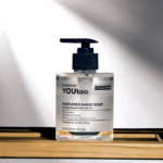 Флакон парфюмированного мыла YOUtoo с дозатором на деревянной полке в лучах света — YOUtoo