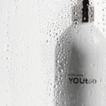 Флакон кондиционера YOUtoo Hydrating Conditioner с каплями воды на стеклянном фоне — YOUtoo