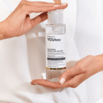 Руки держат флакон мицеллярной воды YOUtoo Calming Micellar Water с открытой крышкой — YOUtoo
