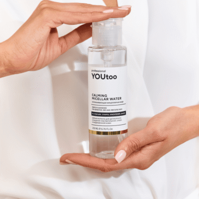 Руки держат флакон мицеллярной воды YOUtoo Calming Micellar Water с открытой крышкой — YOUtoo