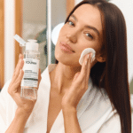 Девушка держит флакон мицеллярной воды YOUtoo и ватный диск у лица — YOUtoo