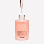 Капля розовой сыворотки SUPER SERUM 5IN1 стекает с пипетки в открытый флакон — YOUtoo